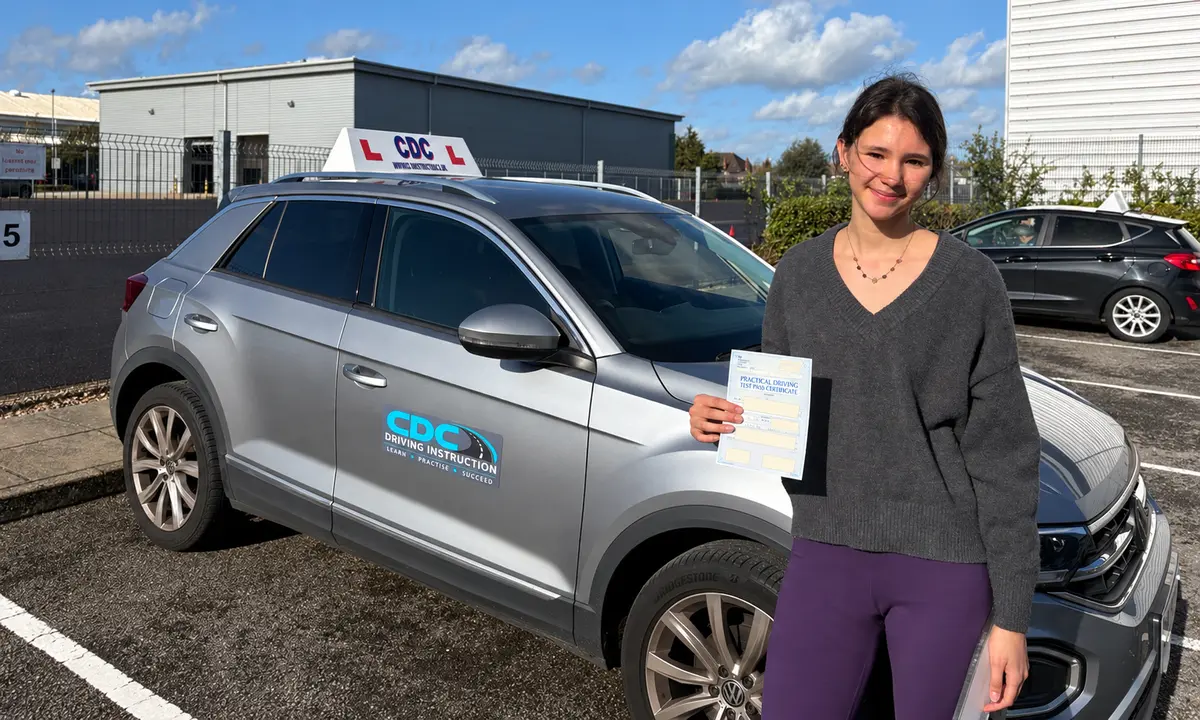 Daisy celebrating her driving test pass beside the CDC teaching car
